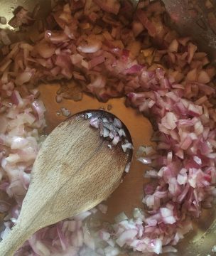 Sauteeing onions for stuffed tomato filling.