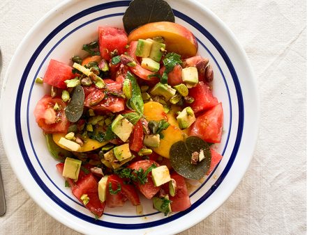 Greek salad with peaches, watermelon, tomatoes, capers and pistachios