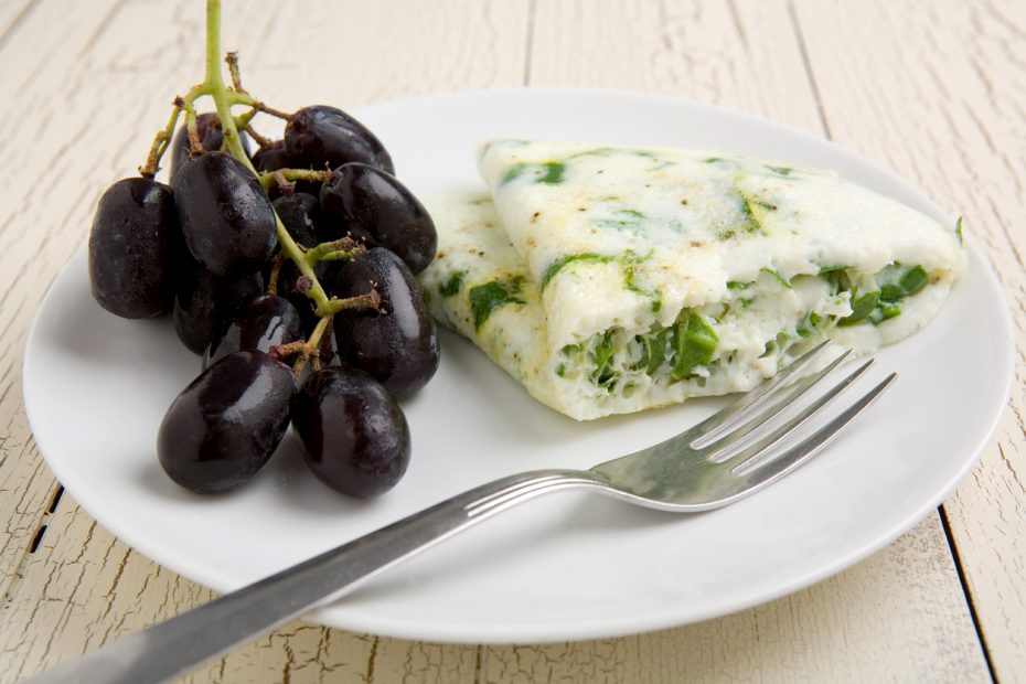 Egg white and spinach omelet with fruit on a white plate