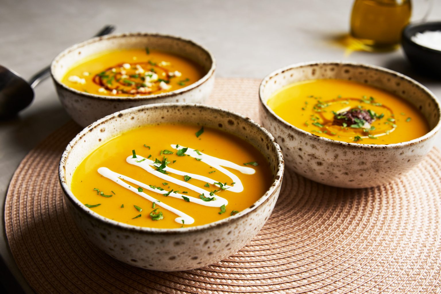 Different variations of carrot soup in separate bowls