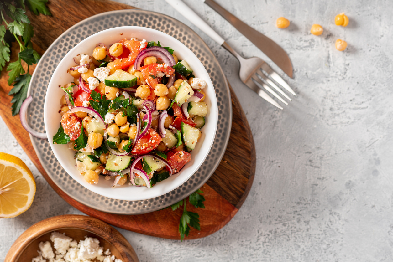 Greek salad with chickpeas, tomatoes and feta cheese. Top view. Grey background.