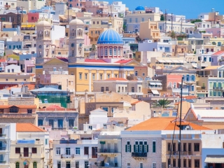 Ermoupolis town, Greece. A town on the side of a mountain. Houses and streets in Greek architecture. Photography for travel and adventure. Cascading arrangement of buildings on the hillside. Ermoupolis town in Syros, Greece.