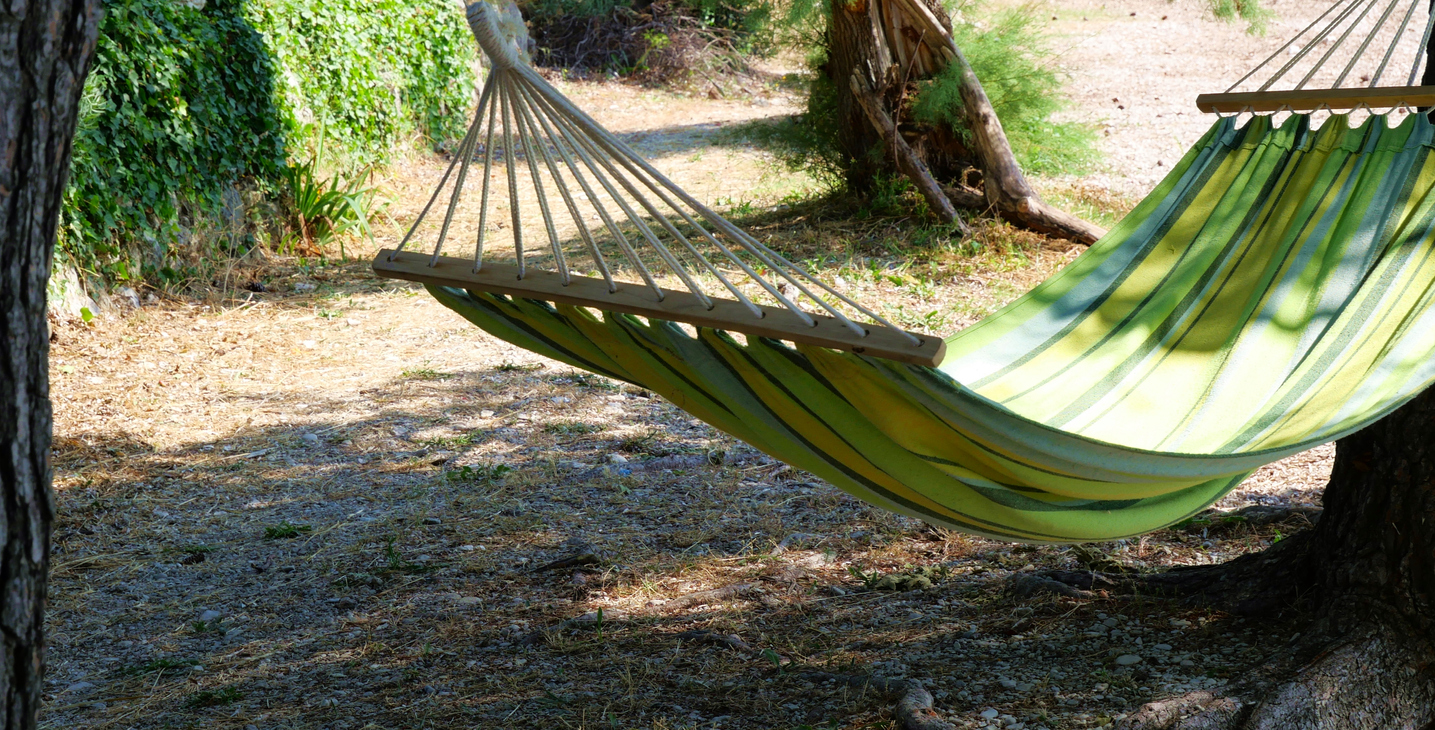 A peaceful scene of a hammock ready for taking a nap in, on the beautiful Ikaria Island, embodying the relaxed lifestyle of the Greek island.